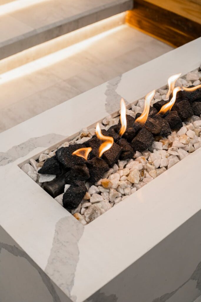 Close-up of a modern indoor gas fireplace with flames and decorative stones.